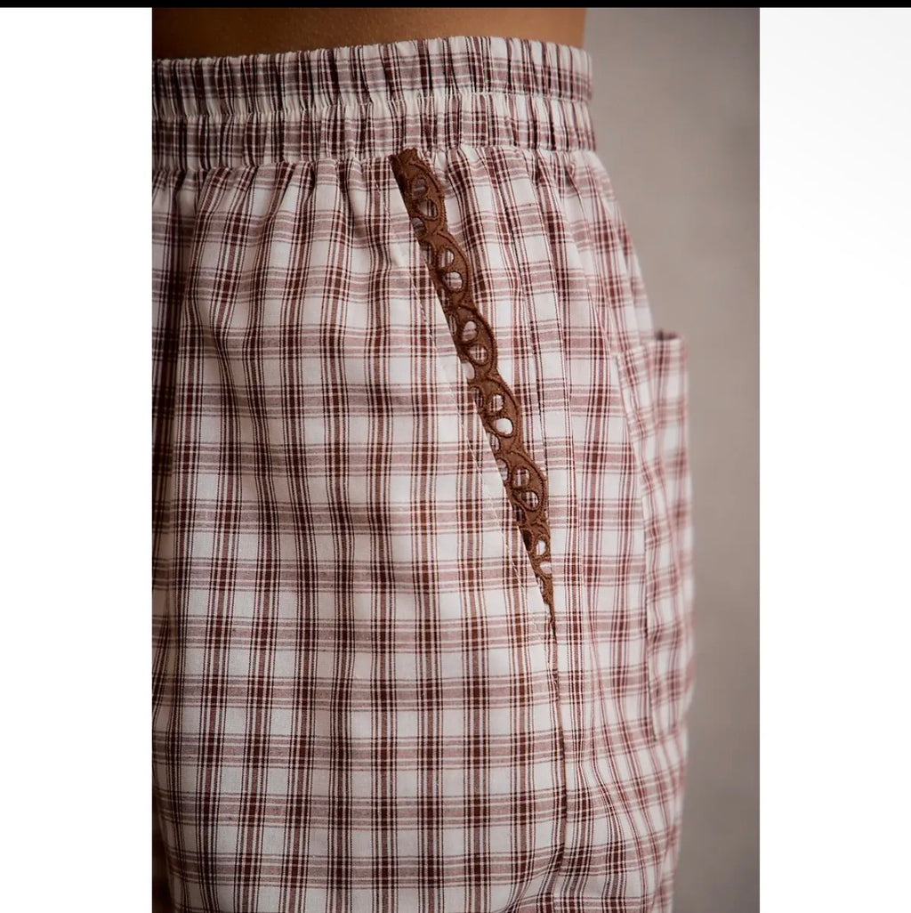 Close-up of brown plaid pants with lace trim pocket detail