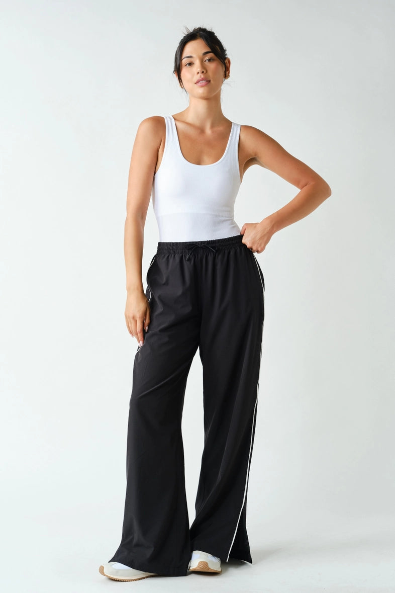 Black wide-leg track pants with white side piping, front view