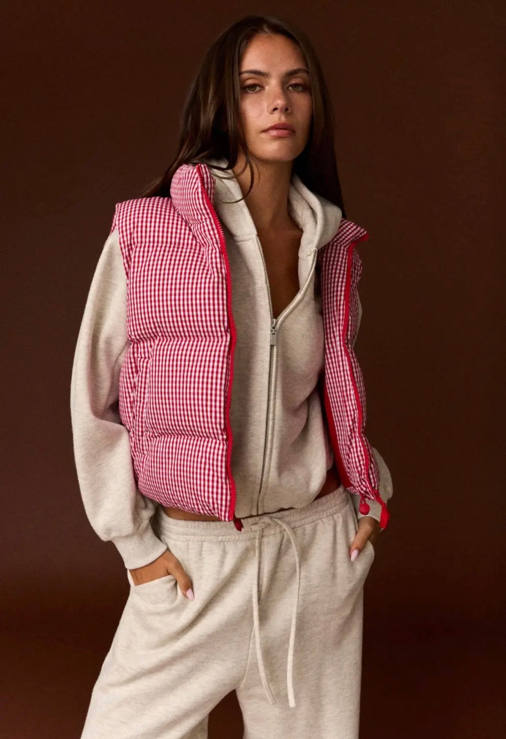 Model wearing red and white gingham puffer vest with cream sweatsuit
