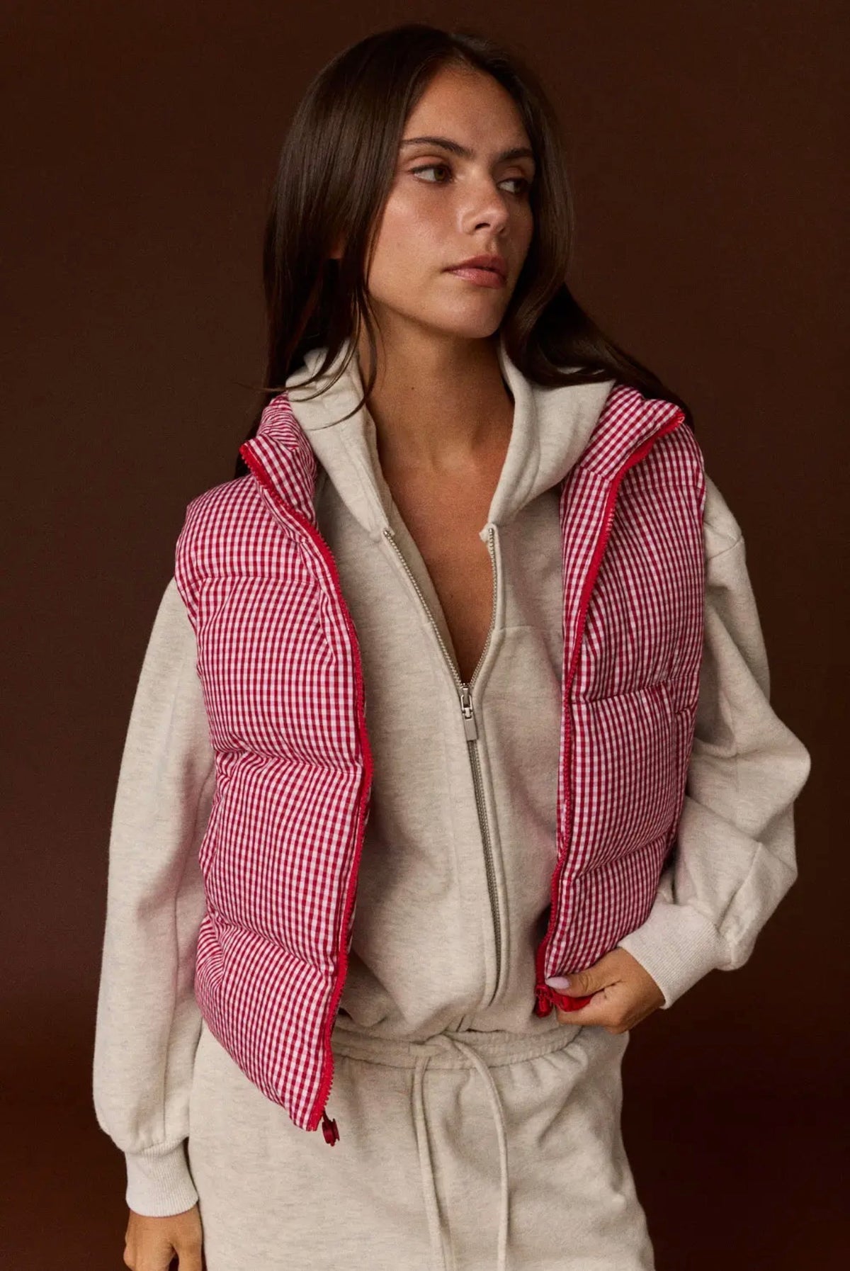 Model wearing red and white gingham puffer vest layered over hoodie